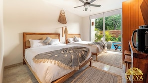 A bedroom with two beds, a ceiling fan, a TV, and a view of a pool. - NHOA 101C 1BR Lux Pool access Aldea Zama (Tulum)