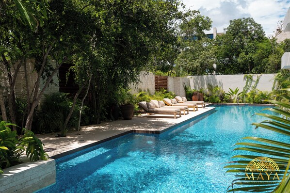A swimming pool with a sun lounger and potted plants.