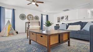 A living room with a blue patterned rug, a wooden coffee table, a grey sofa, and a ceiling fan. - Spacious 4-bedroom house with AC, hot tub, and WiFi in welcoming Tomball  (Tomball)