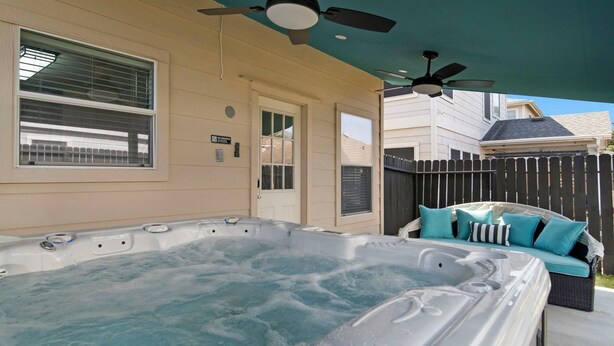 A hot tub with a ceiling fan, a covered patio area, and a seating arrangement with cushions. - Spacious 4-bedroom house with AC, hot tub, and WiFi in welcoming Tomball  (Tomball)