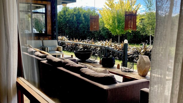 Un espace extérieur moderne, aménagé pour se détendre, avec vue sur un jardin luxuriant et des montagnes.
