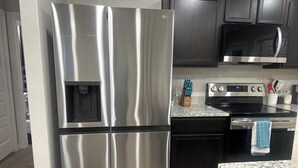 A kitchen with stainless steel appliances, a water dispenser, a microwave, an oven, and granite countertops. - Charming 3-bedroom, 6 beds, 2 bathroom, house with AC and WiFi in awesome Odessa (Odessa)