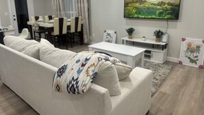 A modern living room with a sofa, a coffee table, and a TV mounted on the wall. - Charming 3-bedroom, 6 beds, 2 bathroom, house with AC and WiFi in awesome Odessa (Odessa)