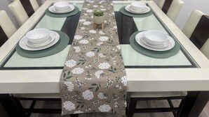 A dining table set with white plates and green placemats, centered with a floral table runner. - Charming 3-bedroom, 6 beds, 2 bathroom, house with AC and WiFi in awesome Odessa (Odessa)