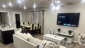 A modern living room with a sofa, coffee table, TV, dining area, and kitchen. - Charming 3-bedroom, 6 beds, 2 bathroom, house with AC and WiFi in awesome Odessa (Odessa)