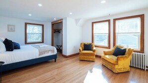 Un dormitorio con una cama, dos sillas y un radiador.