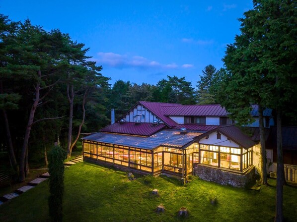 A house with a glass conservatory, a red roof, and a stone foundation. - Village Kagetsuen (Yamanakako)