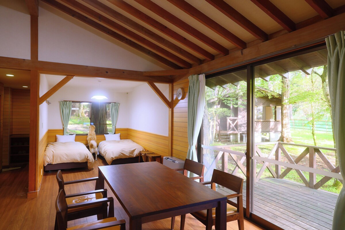 Una habitación con estructura de madera, dos camas, una mesa y sillas.