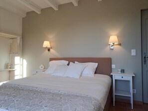 Un dormitorio con una cama grande, dos mesitas de noche y lámparas de pared.