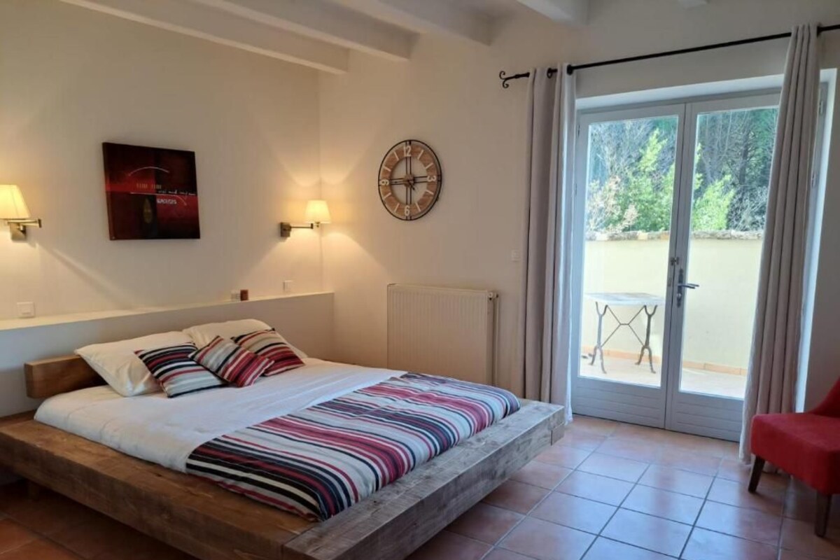 A bedroom with a wooden bed, a clock, a radiator, and a view of the outside.