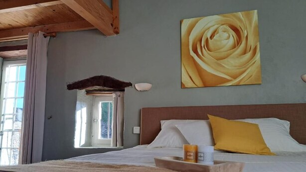 A bedroom with a bed, a window, a painting of a rose, and a wooden headboard. - Logis Hotel Le Clos Des Sullys (Montclus)