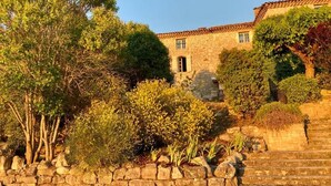 A stone building with a tiled roof, a stone staircase, and surrounding greenery. - Logis Hotel Le Clos Des Sullys (Montclus)