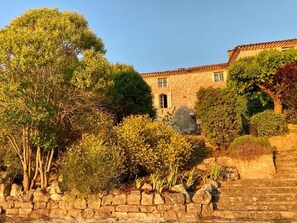 A stone building with a tiled roof, a stone staircase, and surrounding greenery. - Logis Hotel Le Clos Des Sullys (Montclus)
