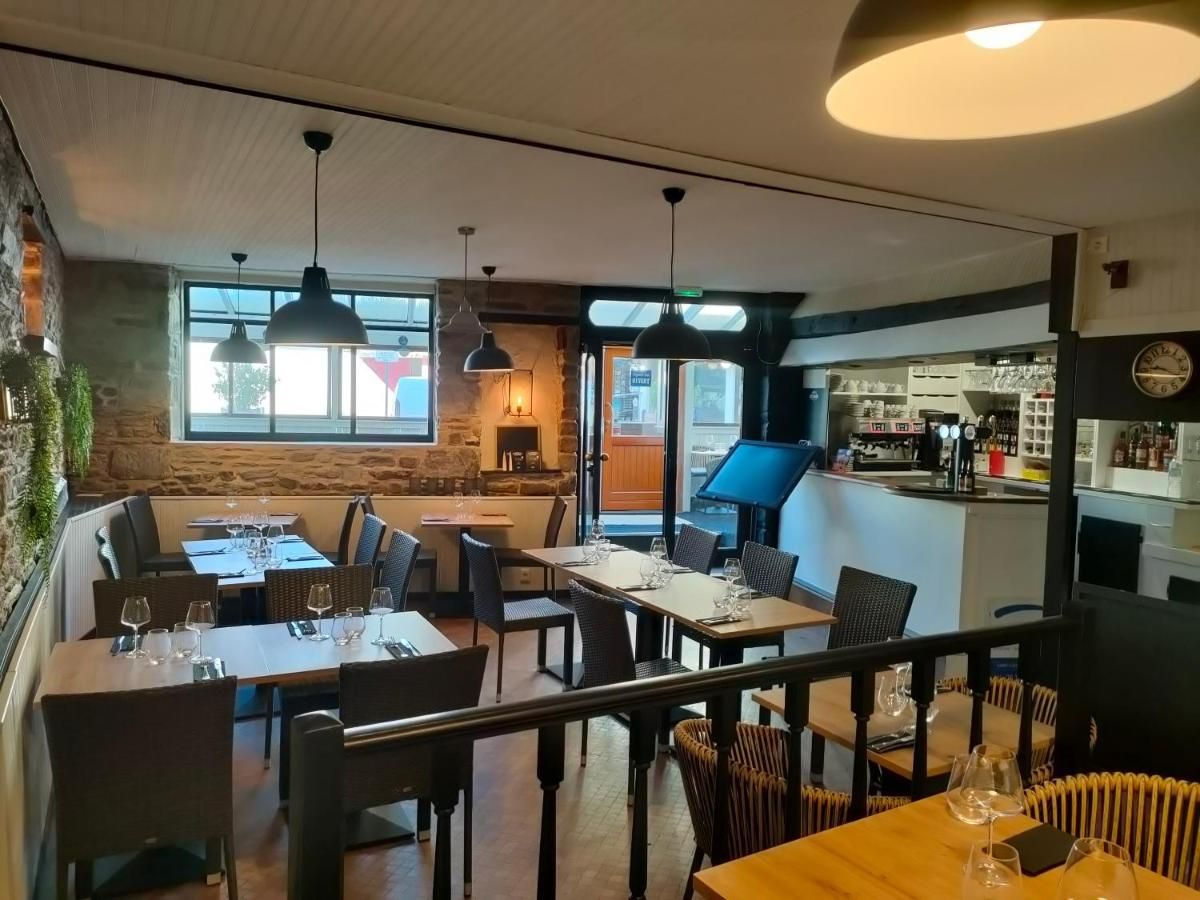Un restaurante con varias mesas y sillas, una zona de bar y vistas a la calle.