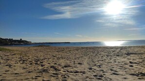 A sandy beach with footprints, a clear sky, and a distant pier with boats. - Logis Hotel De L'esperance (Plevenon)