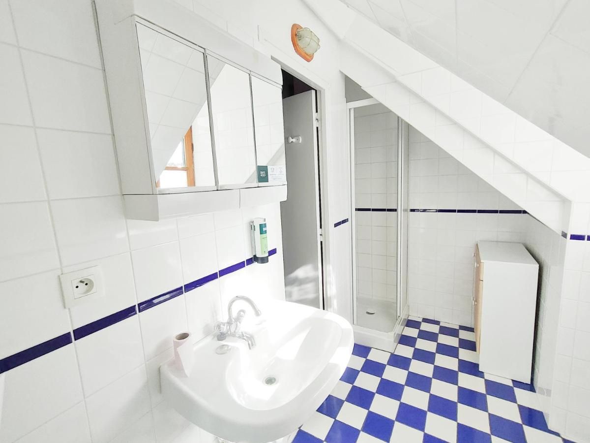 Ein Badezimmer mit weißem Waschbecken, Spiegel und blau gefliestem Boden.