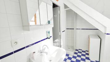 Un baño con lavamanos blanco, espejo y suelo de azulejos azules.