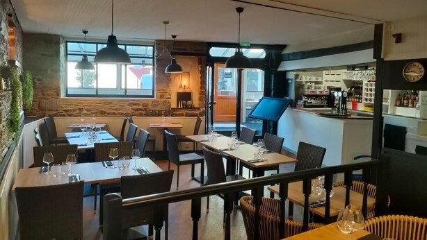 A restaurant with multiple dining tables and chairs, a bar area, and a view of the street. - Logis Hotel De L'esperance (Plevenon)
