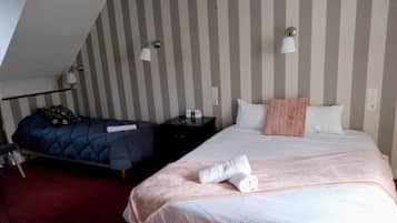 A hotel room with two beds, striped wallpaper, bedside lamps, and a red carpet.