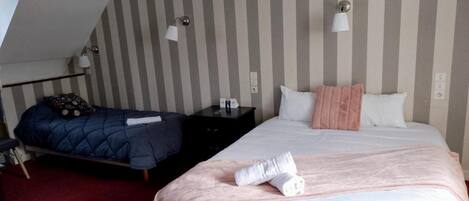 A hotel room with two beds, striped walls, and bedside lamps.