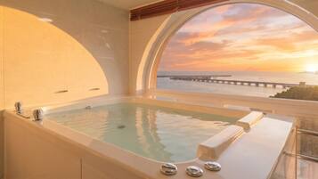 Un área de spa con una bañera grande y vistas al atardecer sobre el océano.