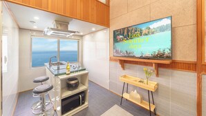 A compact kitchen with a view of the sea, a built-in oven, a microwave, and a bar stool. - Samcheok Peacehousing Spa Pet Pension (Samcheok)