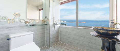A modern bathroom with a toilet, shower, and sink with a decorative bowl.