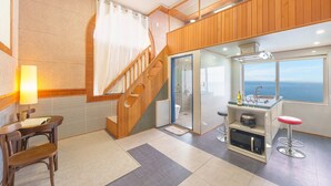 A modern kitchen with a view of the ocean, a wooden staircase, and a dining area with a table and chairs. - Samcheok Peacehousing Spa Pet Pension (Samcheok)