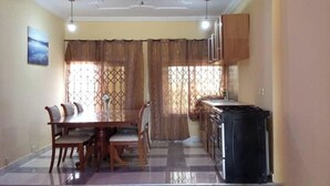 A dining area with a table, chairs, a refrigerator, and a kitchen counter.