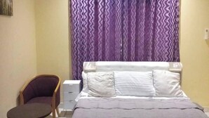 A bedroom with a bed, a chair, and a small table.