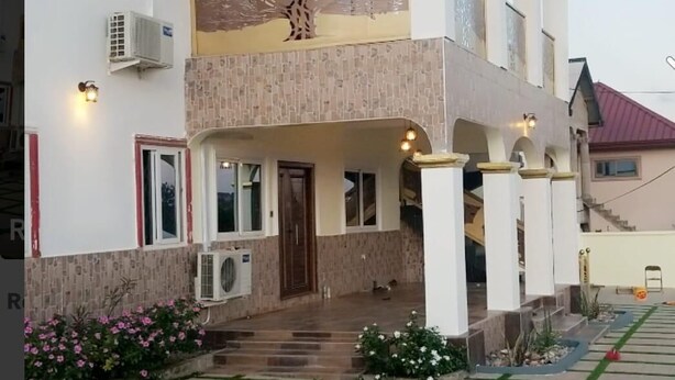 A two-story house with a balcony, air conditioning units, and a tiled entrance.