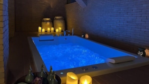 Ein Spa-Raum mit Whirlpool, Kerzen und einer Ziegelwand.