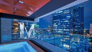 Interior moderno de un hotel con un balcón de cristal que da a una vista nocturna de la ciudad.
