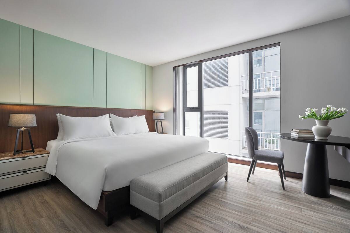 A modern hotel room with a large bed, a desk, and a chair.