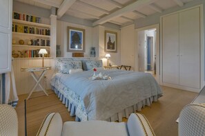 A bedroom with a large bed, a bedside table, a chair, a bookshelf, and a door. - Villa Federica 17 by Anita Villas (Manciano)