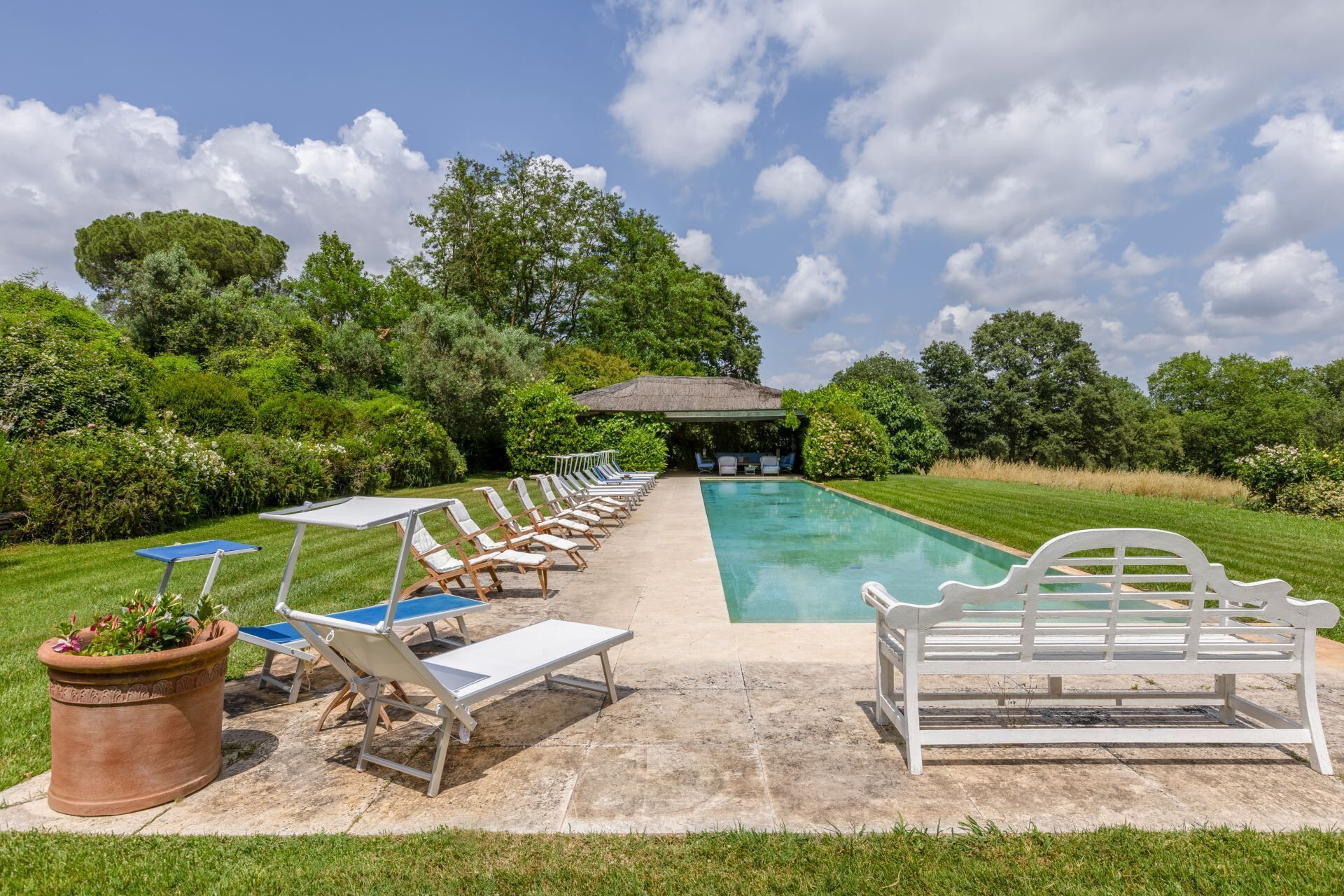 Ein Poolbereich mit Liegestühlen und einer Pergola.