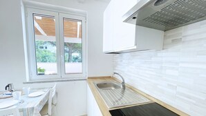 Une cuisine de taille réduite, dotée d’une fenêtre, d’un évier et d’une cuisinière.