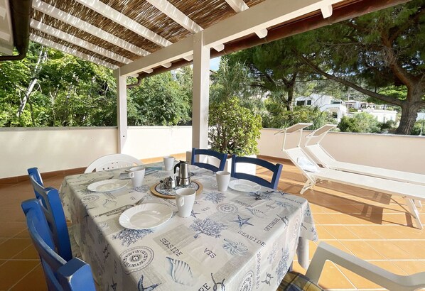 An outdoor patio with a table set for dining, chairs, and a sun lounger. - Cavoli beach, a few steps from the wonderful sea! (Campo nell'Elba)