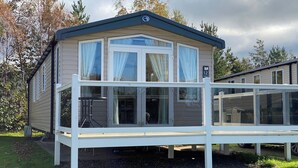 Una casa móvil con un porche cubierto, ventanas amplias y un cartel con el número 12.