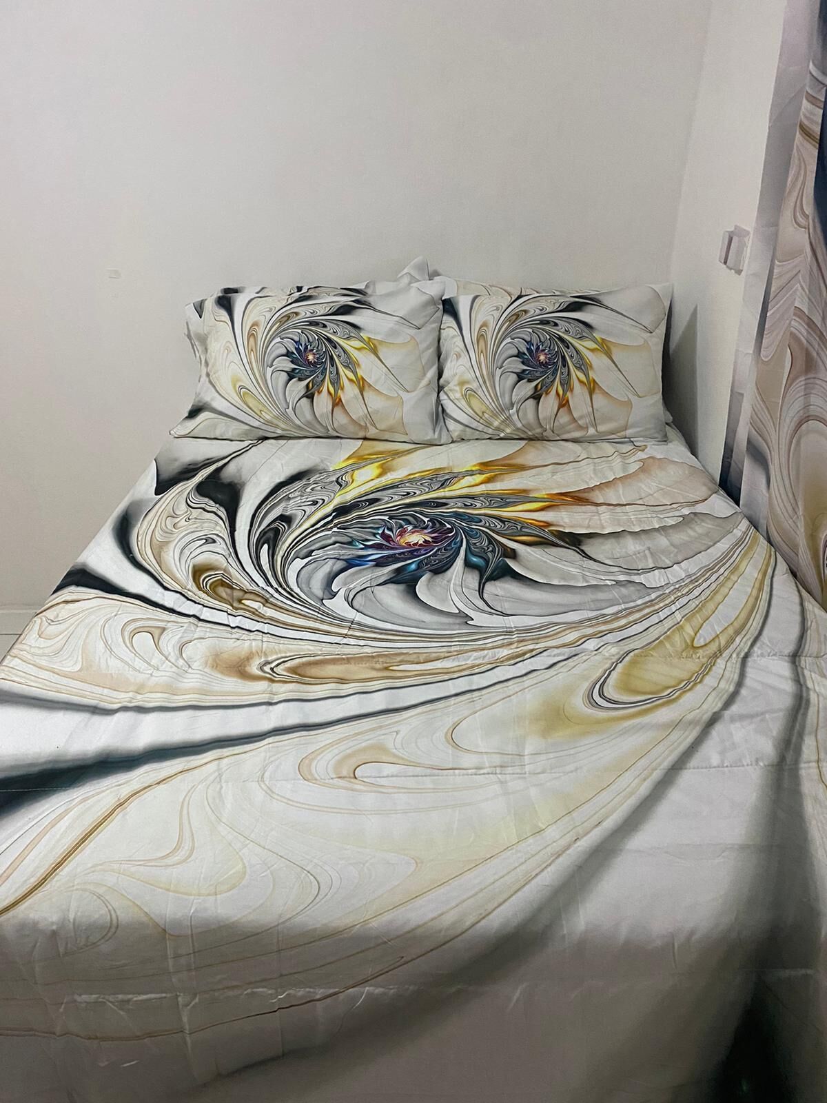 Una cama con colcha y almohadas a juego en tonos blanco y beige.