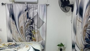 Une chambre à coucher avec un lit, une télévision, un ventilateur et une petite plante.