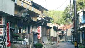 En traditionell japansk byggnad med en skylt, en liten trädgård och en gata.