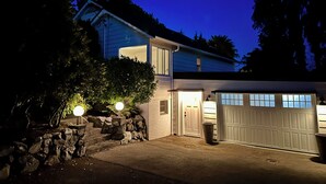 Une maison à deux étages avec un garage, des marches en pierre et une entrée bien éclairée.