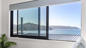 Una habitación con un amplio ventanal que ofrece vistas al mar y a las colinas.
