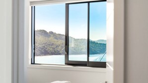 Un dormitorio con un amplio ventanal con vistas al paisaje costero.
