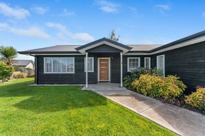 A two-story house with a dark exterior, a front porch, and a well-maintained lawn.
