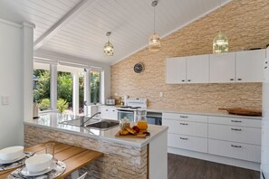 Enjoy cooking in this well-lit kitchen with a large island and sink, surrounded by cabinetry and a stone accent wall.