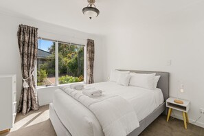 Relax in a serene bedroom with a large bed and a window with curtains.