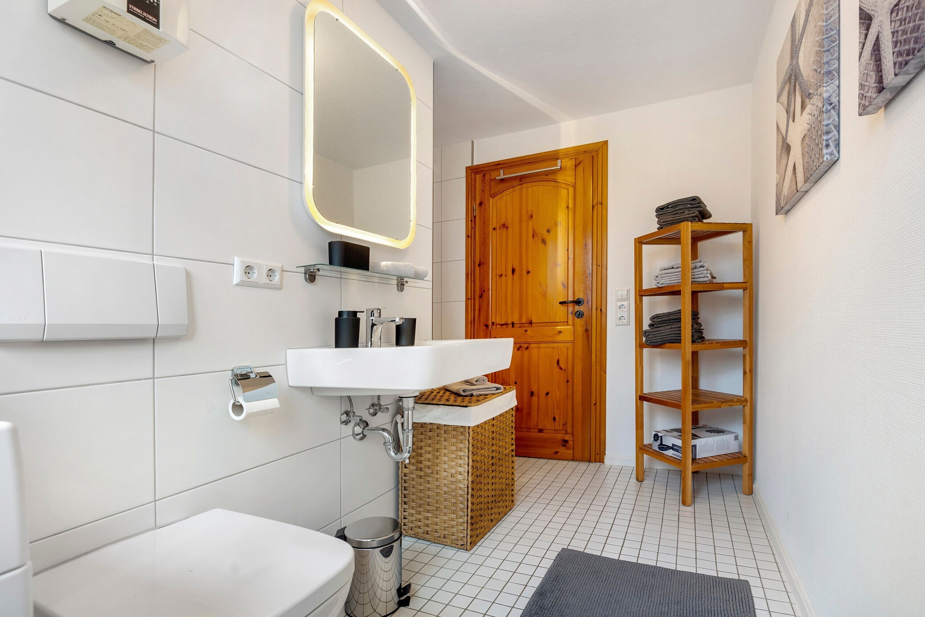 A bathroom with a white sink, mirror, and wooden door.