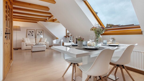A modern loft-style room with a dining area, white furniture, and a skylight. - Apartment 'Hannover Südstadt-Perle' with Private Garden and Wi-Fi (Hannover)